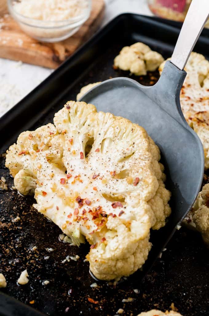Seasoned, roasted cauliflower slice being turned with a spatula.