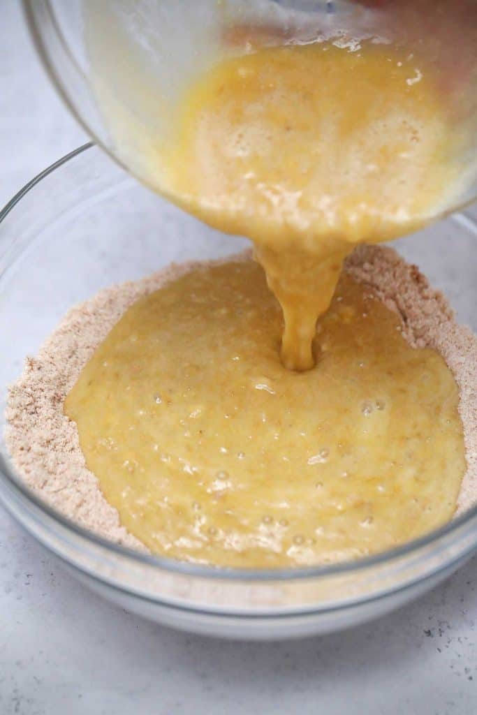 Mashed banana mixture being poured into a flour mixture.