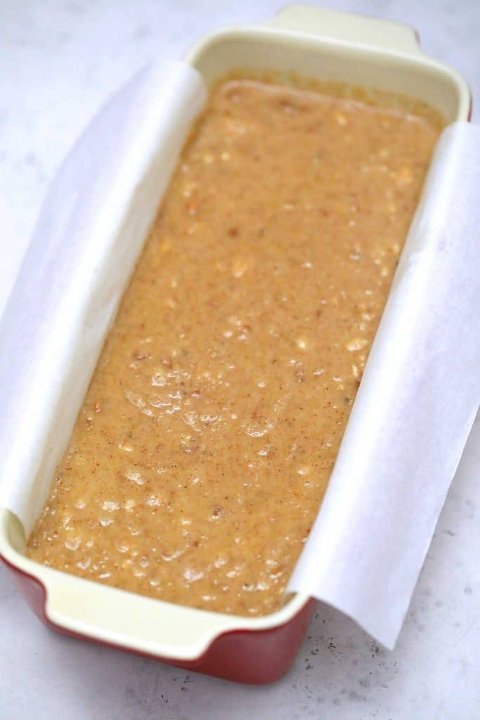 Banana bread batter in loaf pan with parchment paper.
