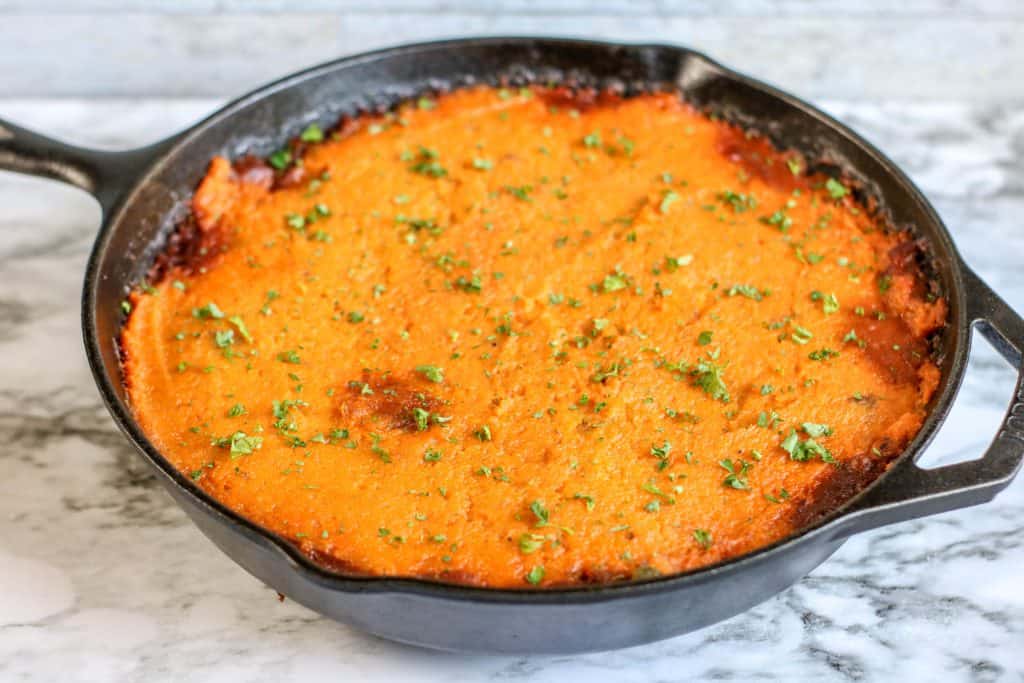 Sweet Potato Shepherd's Pie in a black cast iron skillet on a white marble background.