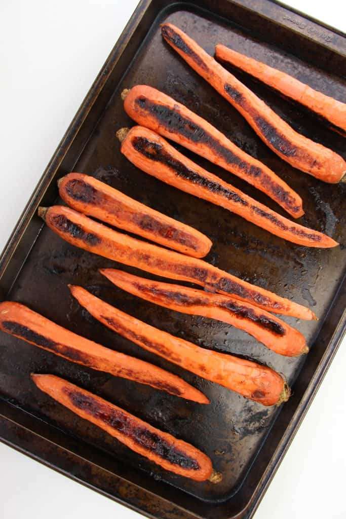 Charred whole carrots on a cookie sheet.