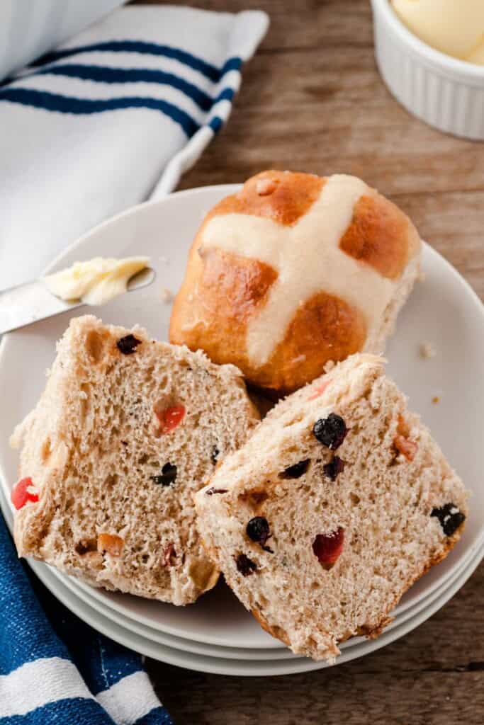 Hot cross buns cut in half on a white plate.