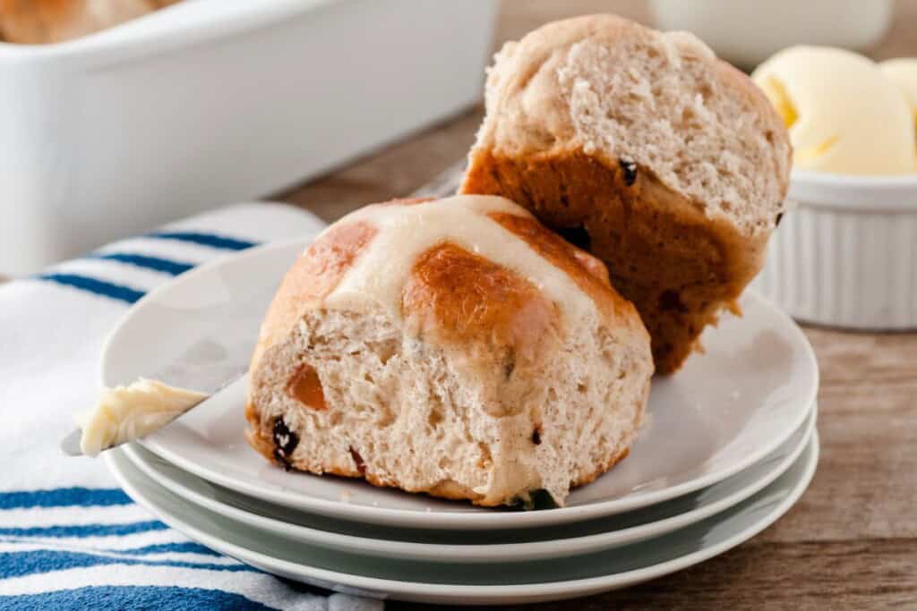 two hot cross buns stacked on white plates.