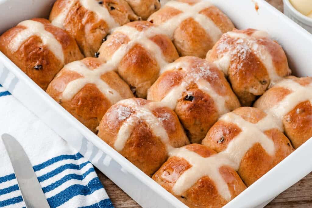 old fashioned hot cross buns in a white ceramiic baking dish.