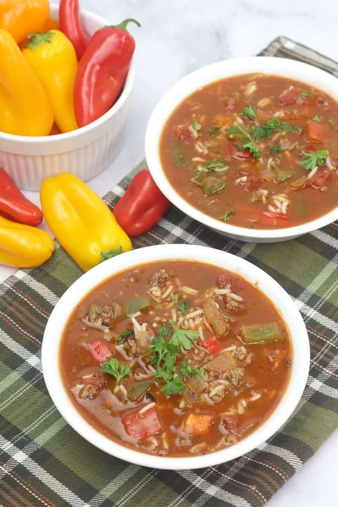 2 bowls of soup with red and yellow peppers beside it.