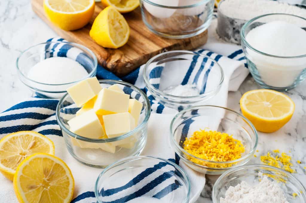 Ingredients for lemon dessert on a white marble background with a white towel with blue stripes.