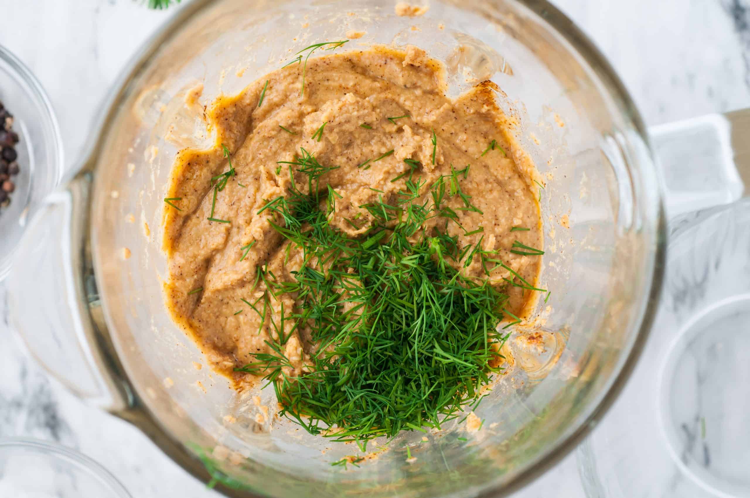 fresh dill on top of blended chickpeas in a blender