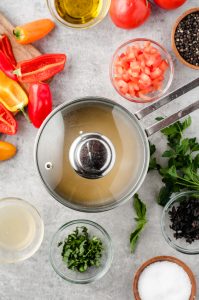 Covered pot with herbs and peppers around it