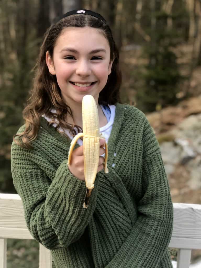 Beautiful young girl eating a banana.