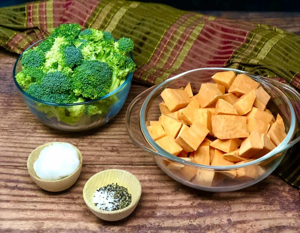 Broccoli and sweet potatoes on a wooden background with coconut oil, salt and pepper.