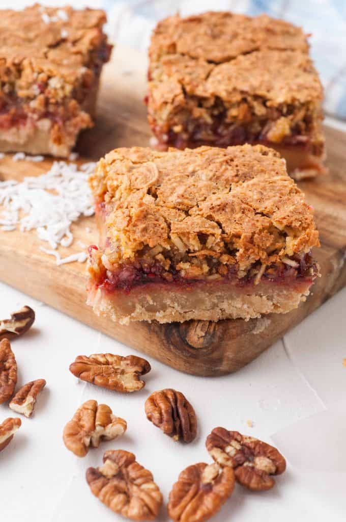 Cut coconut raspberry bars on a cutting board.