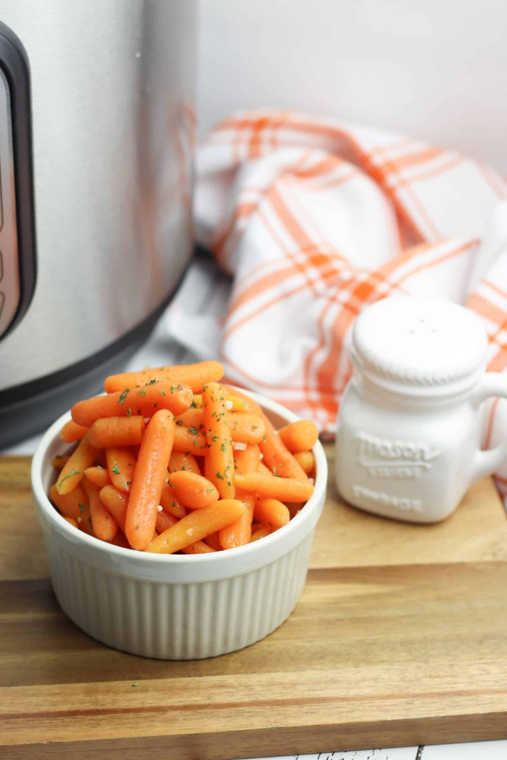 Instant Pot Carrots in a white bowl with white salt shaker beside them.