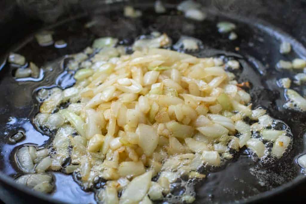 Onions saut&eacute;ed in butter in a black iron skillet.
