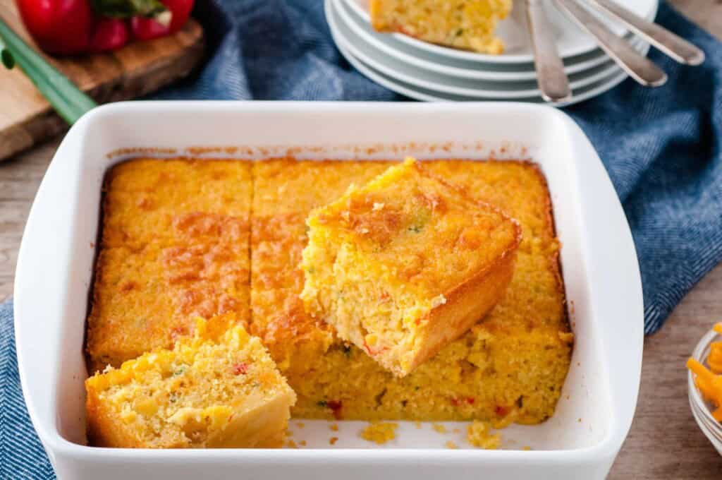 Easy Mexican Cornbread in a white ceramic baking dish with 2 pieces cut out.