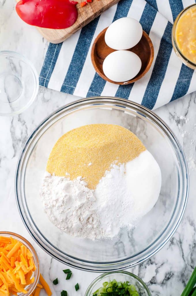 Cornmeal, Flour and baking powder and baking soda in a clear glass bowl.