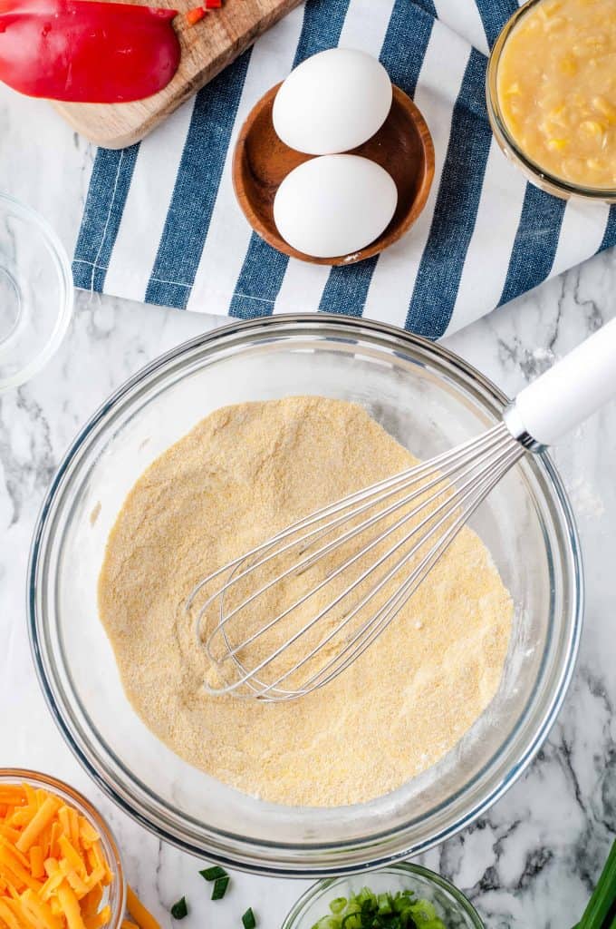 Cornbread mix in a bowl with a whisk on top.