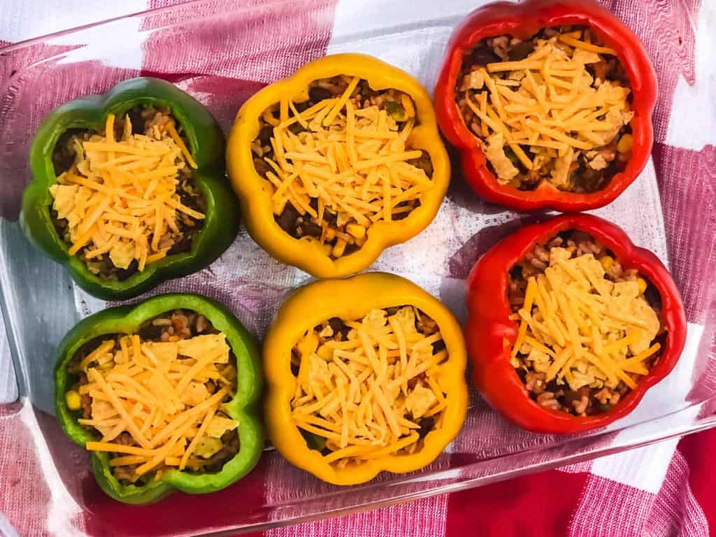 Overhead shot of stuffed stoplight peppers with cheese on top.