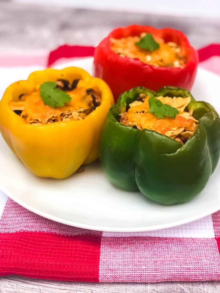 Angela shot of red, yellow and green bell peppers topped with cilantro leaves.