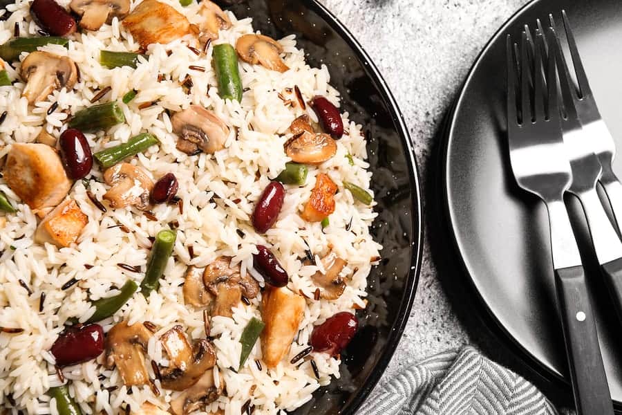 Delicious rice pilaf with chicken and vegetables on grey table, closeup