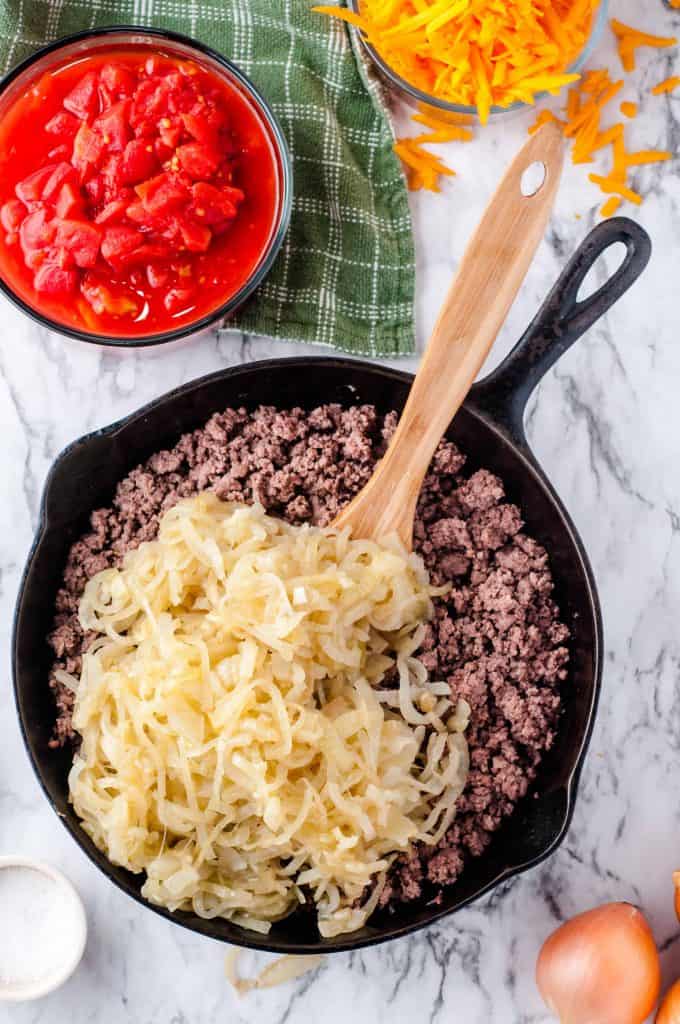 Cooked onions on top of beef in skillet