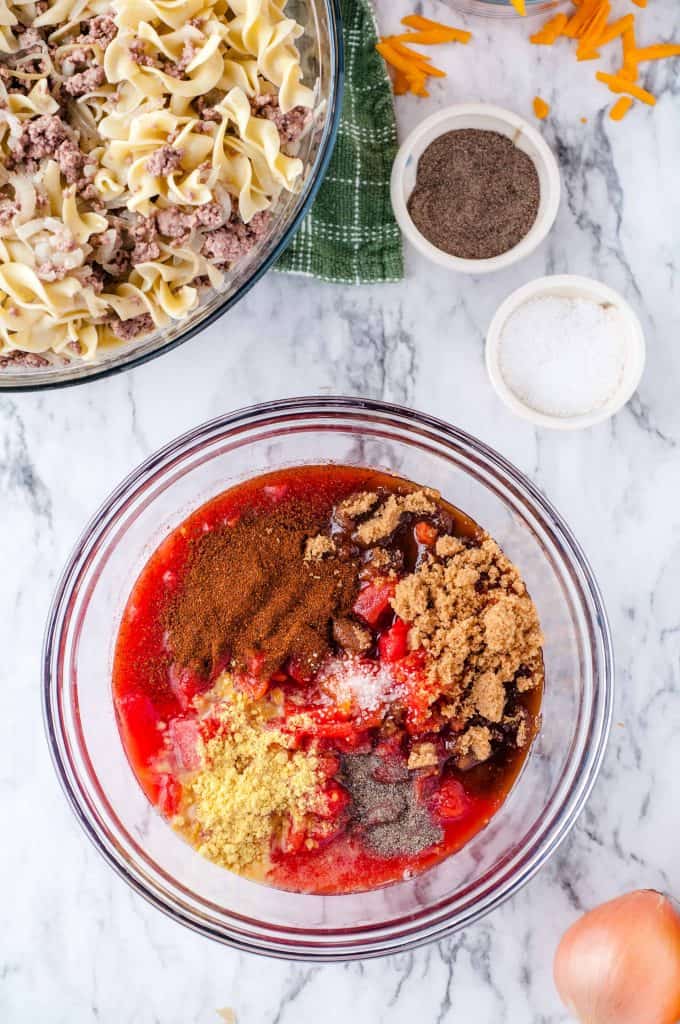 Spices and canned tomatoes in a bowl for the cheesy beef and noodle casserole