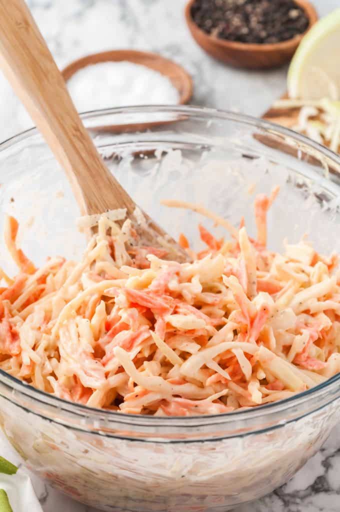Classic creamy coleslaw recipe with dressing being mixed in to it.