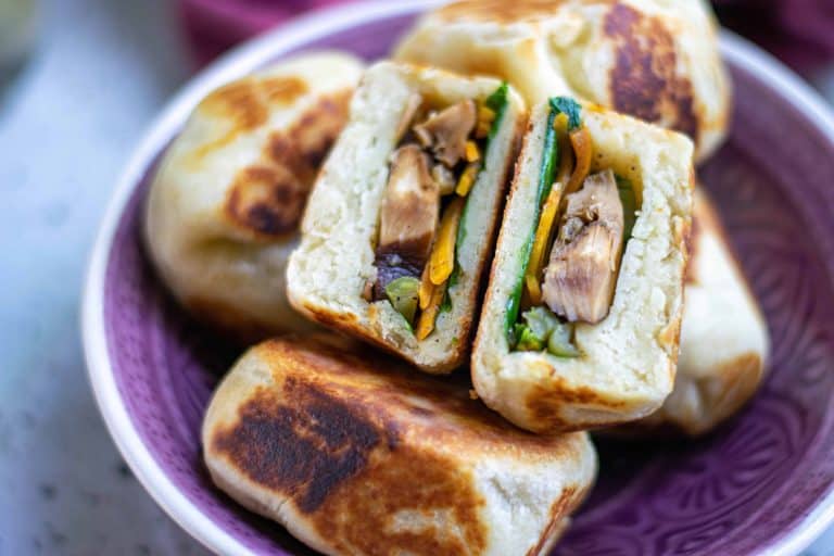 Vegan Bao Buns on a purple plate with one cut in half.