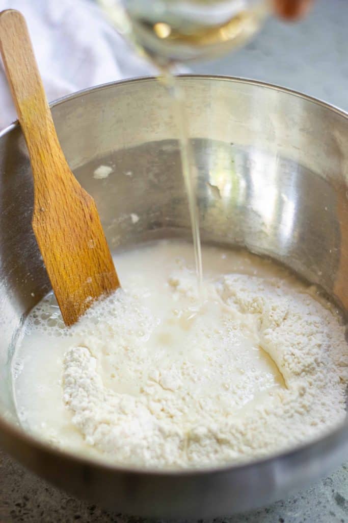 Flour, water and oil in a stainless steel bowl.