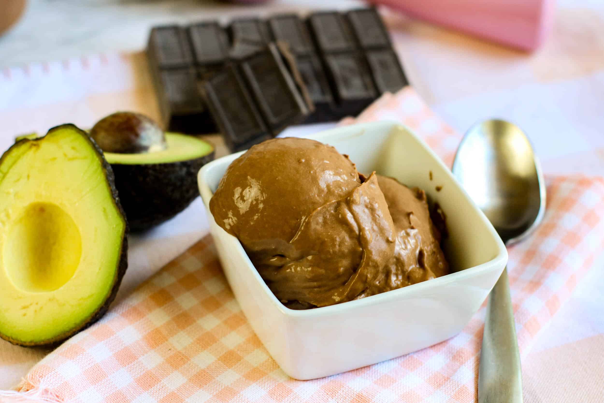 Chocolate Avocado Ice Cream on an orange checked dish towel with an avocado cut in half and a spoon by the side of the dish.