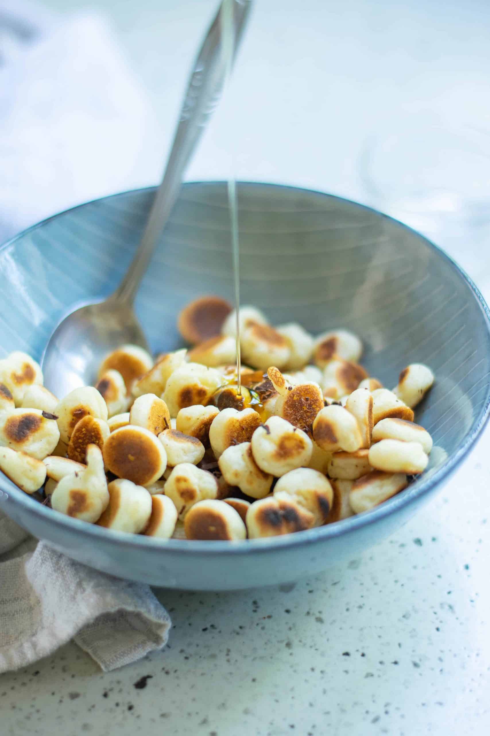 Mini Pancakes cereal in a bowl with syrup being poured onto them.