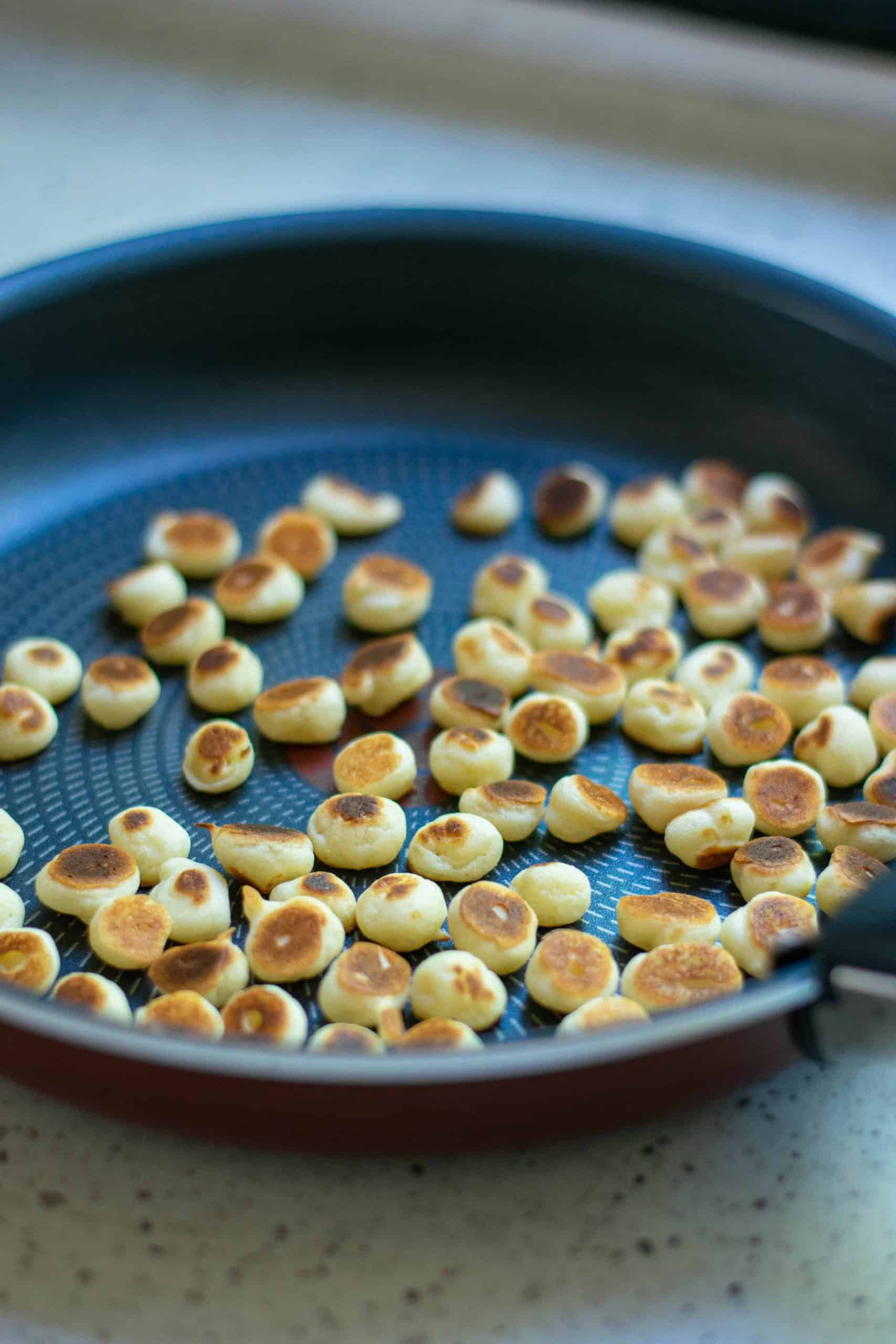Mini pancakes cooked in a frying pan.