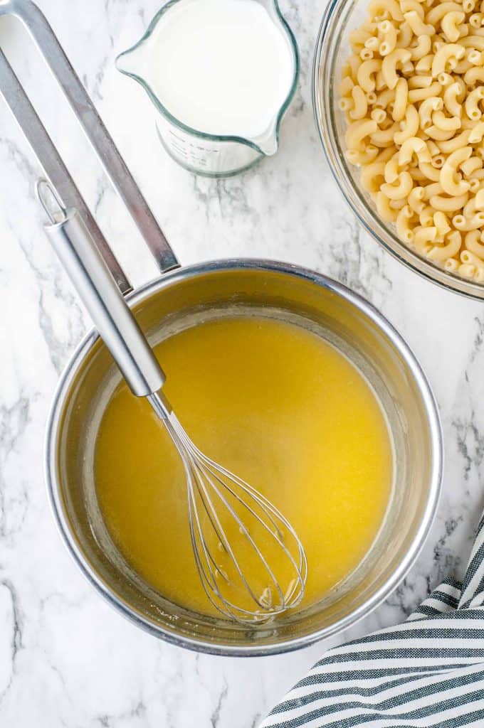 Butter melted in a pan with macaroni in strainer in upper right hand corner.