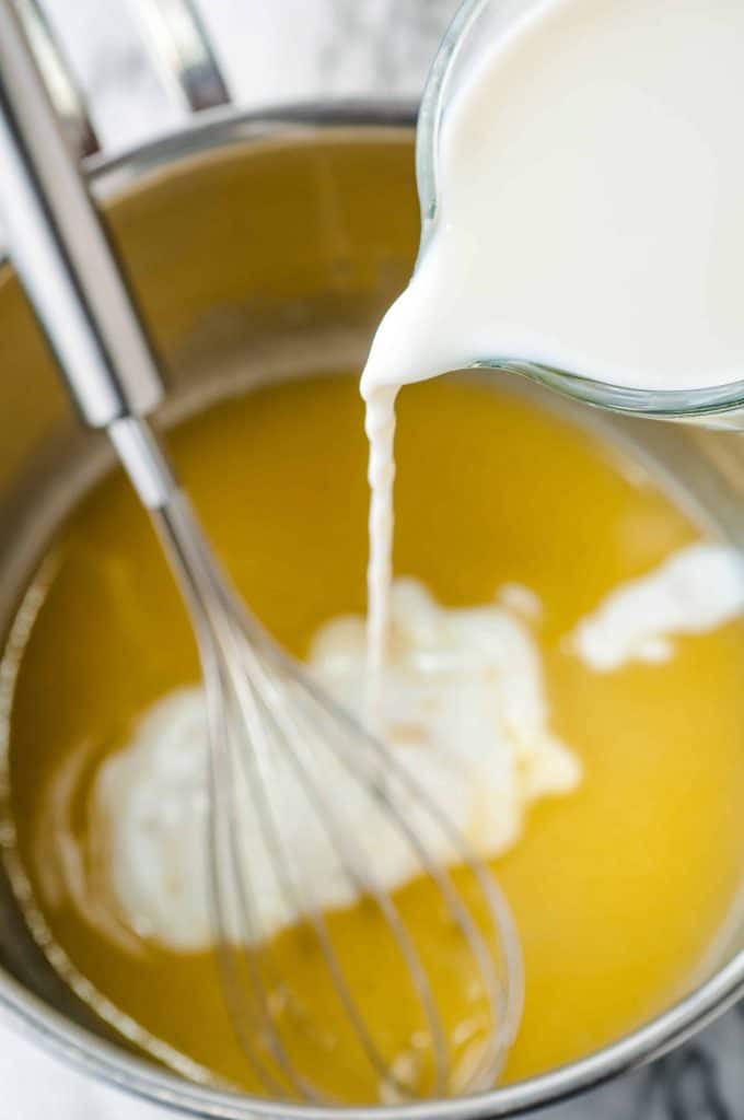 Milk being poured into butter mixture in saucepan.