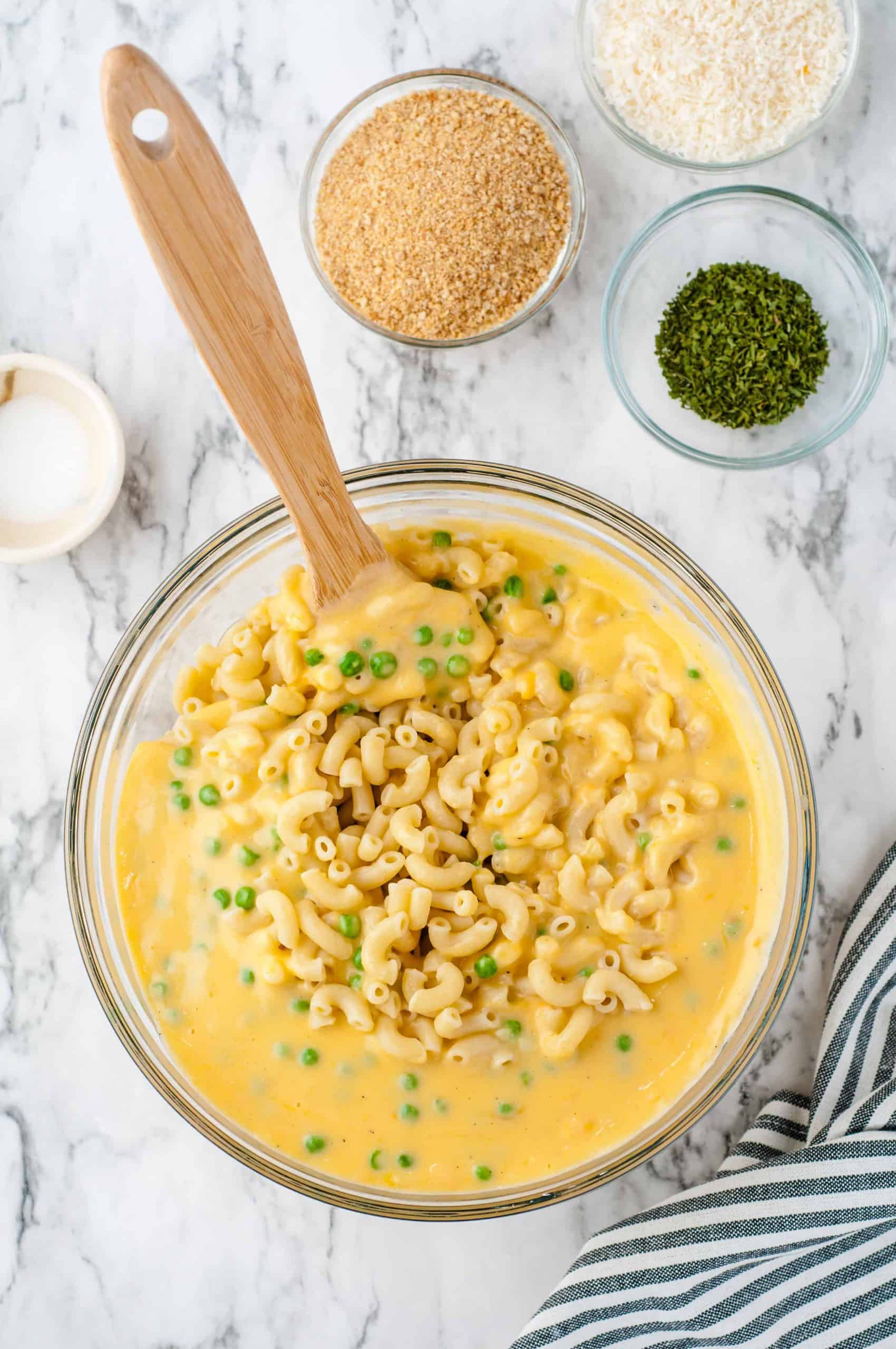 Macaroni and cheese sauce with peas in a large glass bowl.