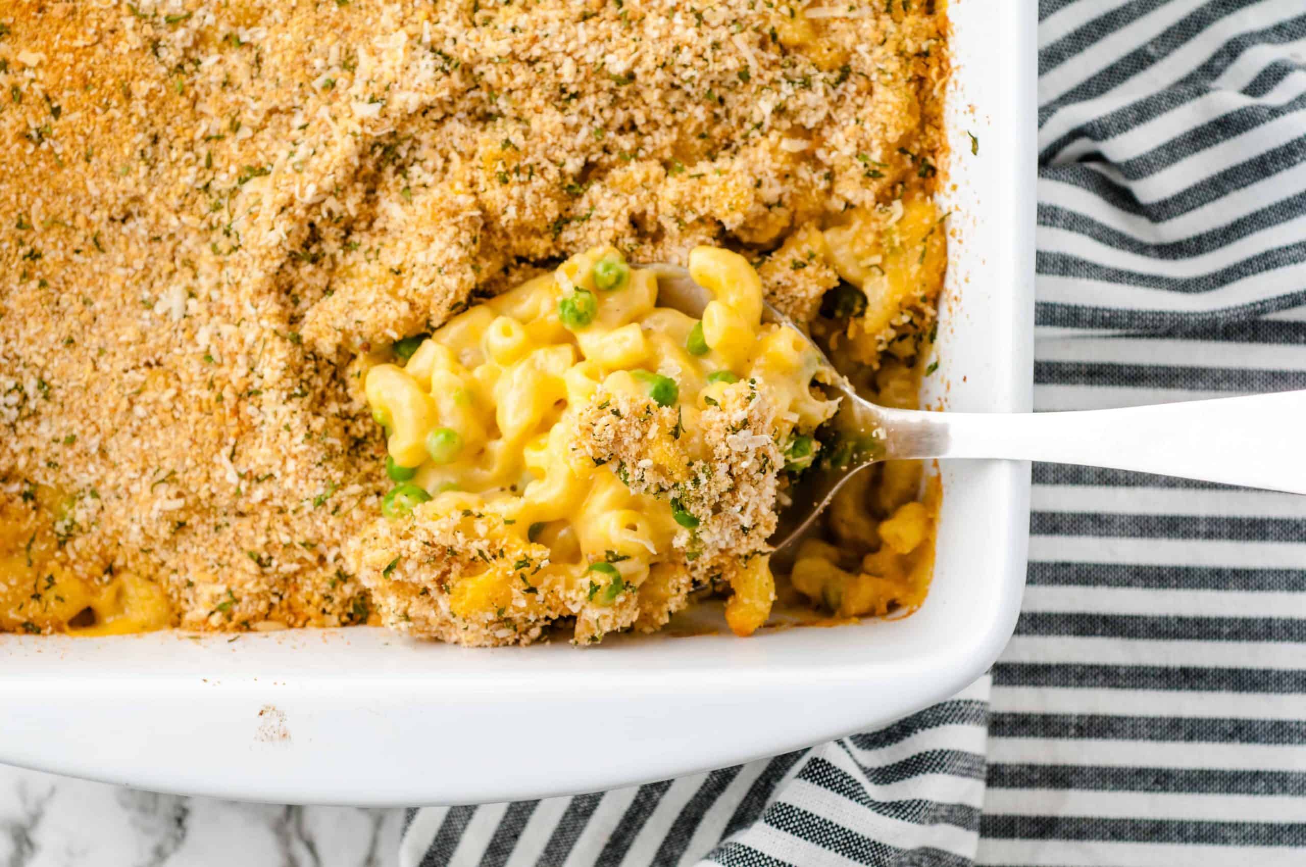 Baked macaroni and cheese with gouda casserole in white dish with a serving spoon in it.