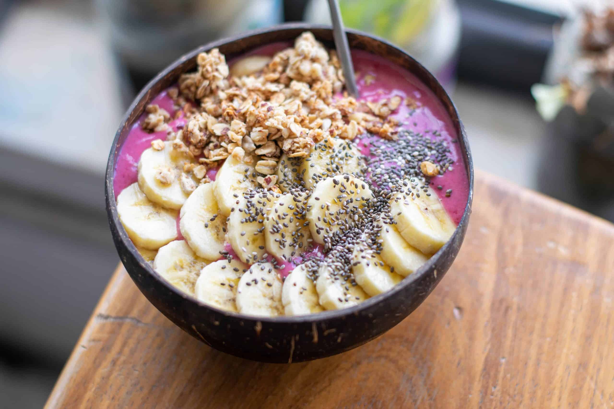 Overhead shot of pink smoothie bowl with bananas, granola and chia seeds.