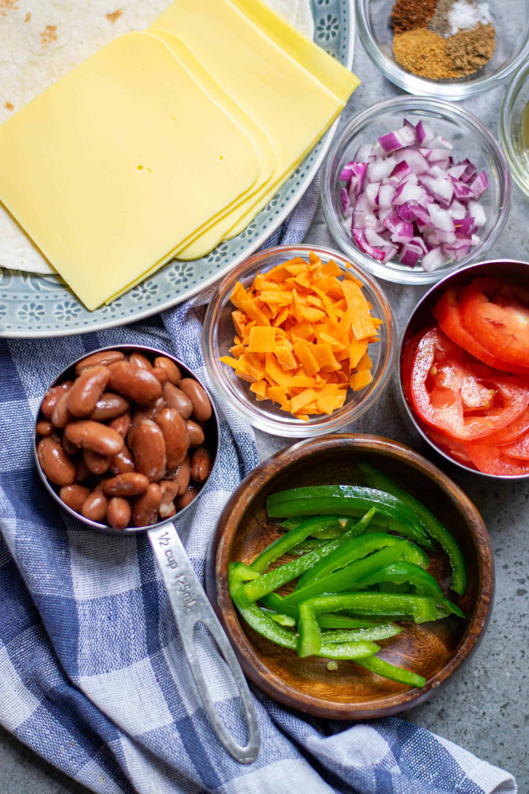 Vegan cheese, kidney beans, carrots, red onion, bell pepper and tomato over head photo of these ingredients.