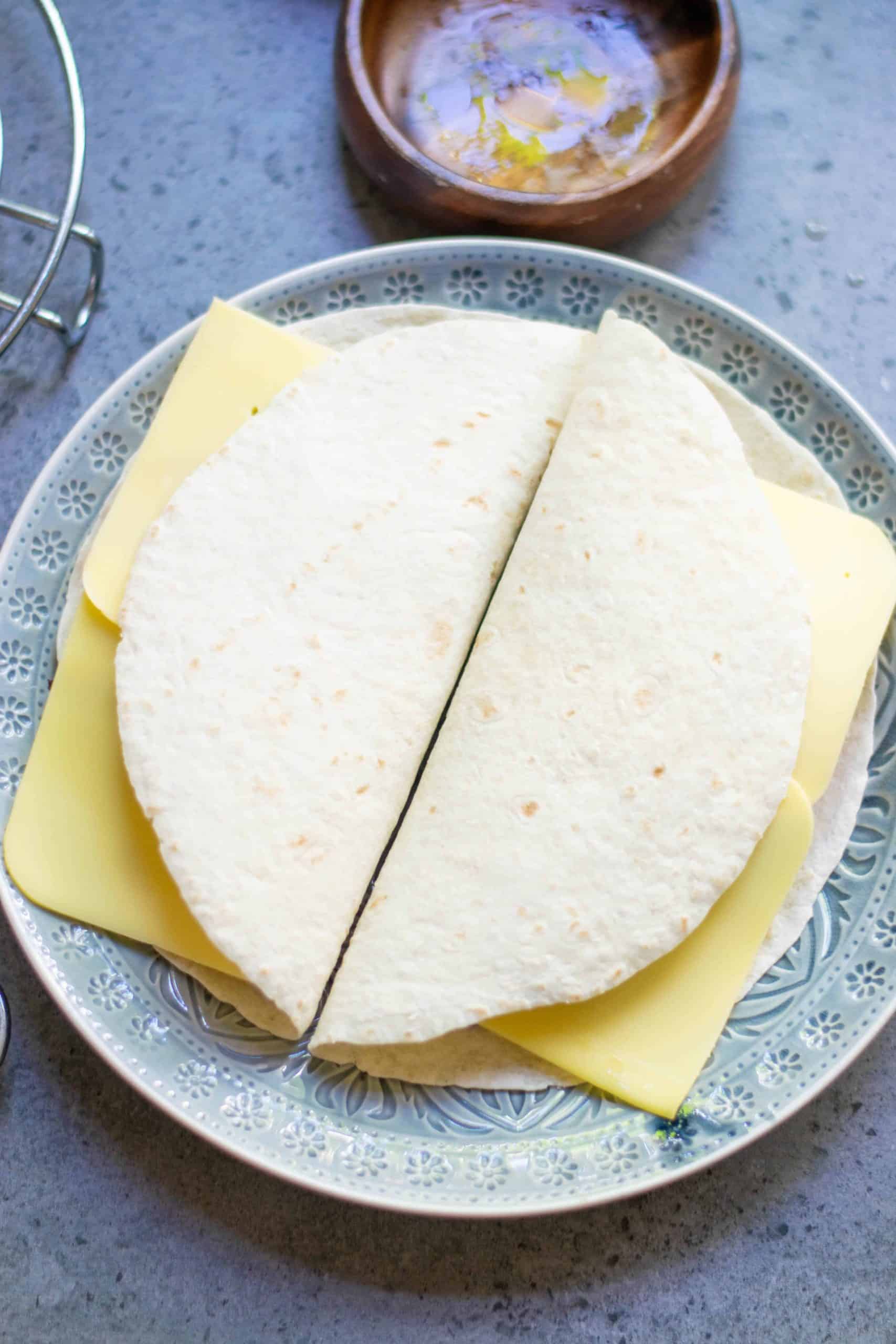 Tortillas folded in half with vegan cheese sticking out of the edges.