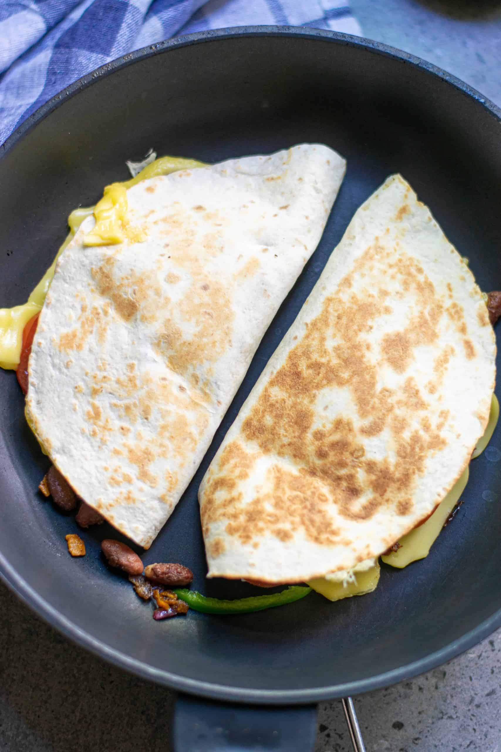 Crispy golden quesadillas in a frying pan.