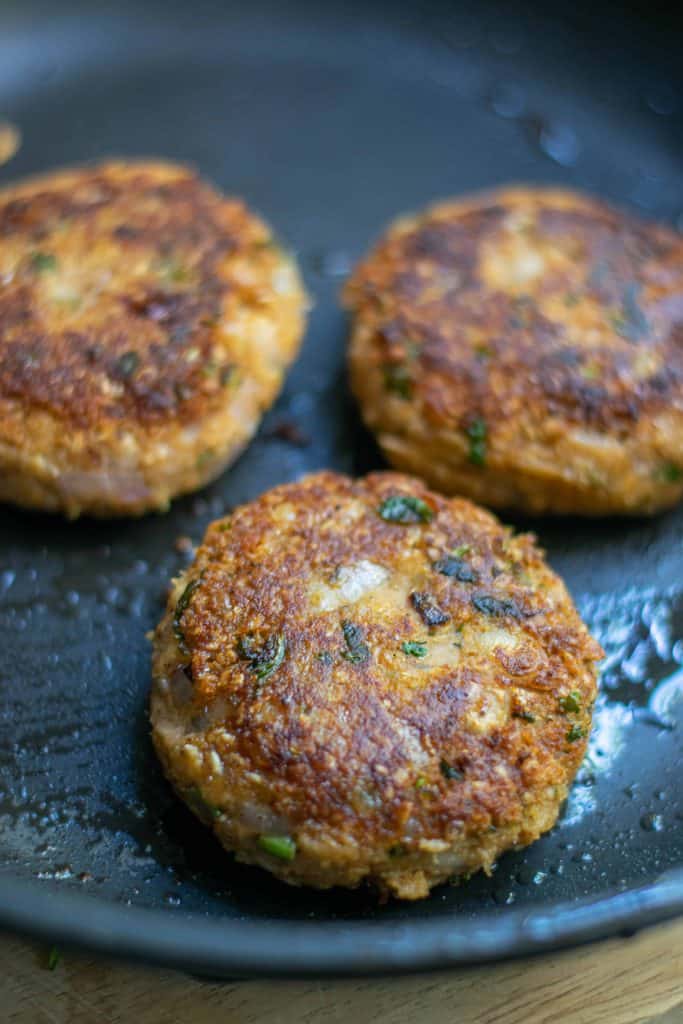 Closeup of cooked Vegan White Bean Burgers in a frying pan.