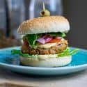 Vegan white bean burger on a Lue plate with an olive on top.