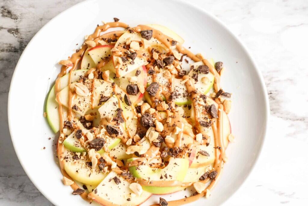 Overhead shot of apple nachos on a white plate.