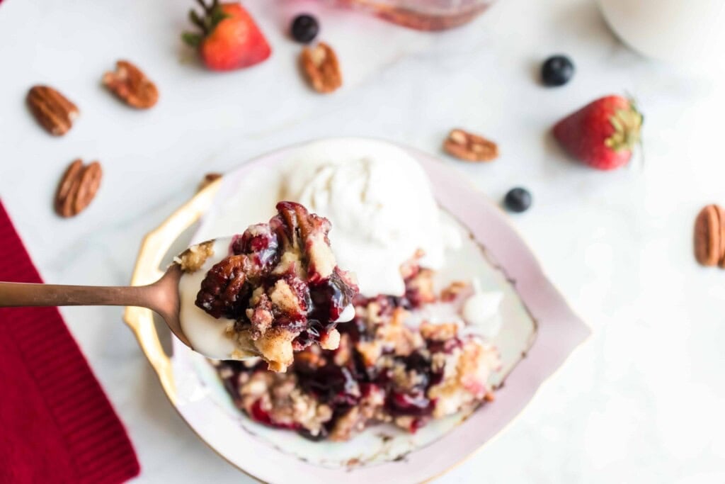 Closeup of blueberry strawberry dump cake on a spoon with ice cream.
