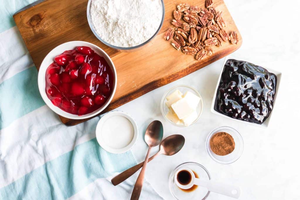 Overhead shot of cherry pie and blueberry pie filling, flour, butter, and pecans.