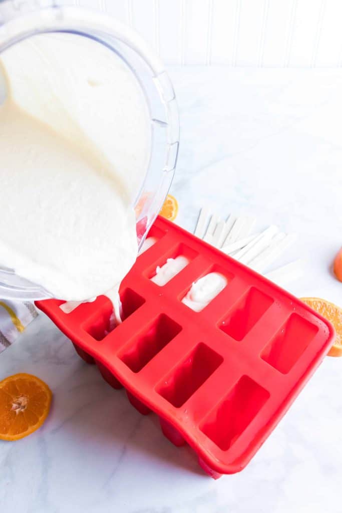 Pouring creamy popsicle mixture into a mold.