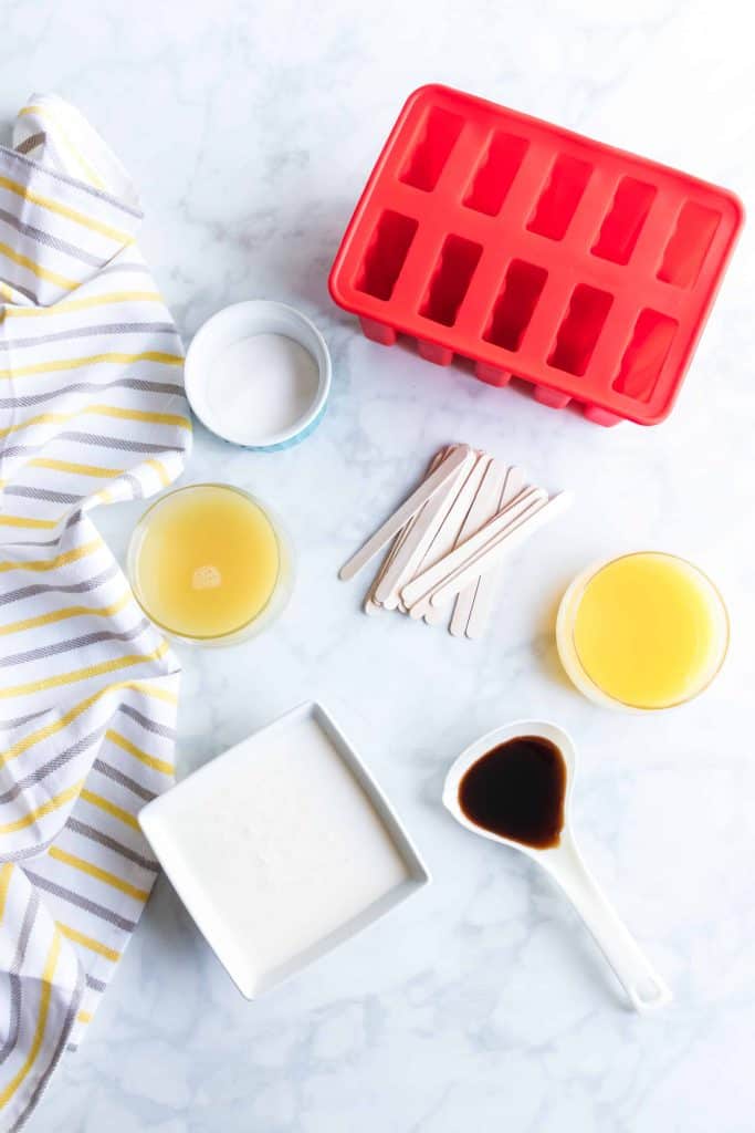 Ingredients and supplies for orange pineapple popsicles