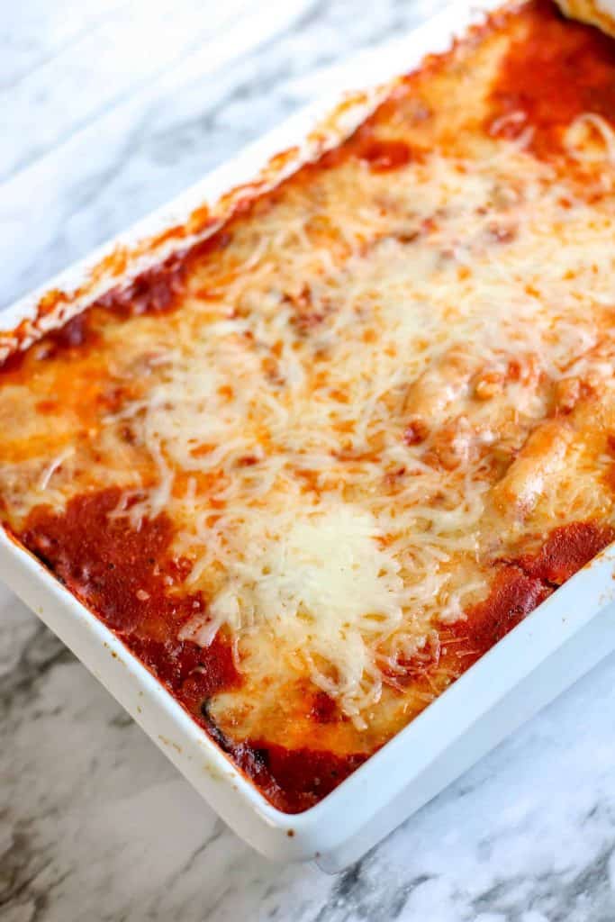 Full pan of cheesy lasagna in a white ceramic baking dish.