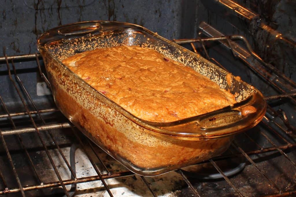 Strawberry bread baking in glass bread dish in the oven.