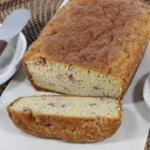 Keto Strawberry Bread on a cutting board with a stick of butter and knife on one side and a bowl of strawberries on the other side.