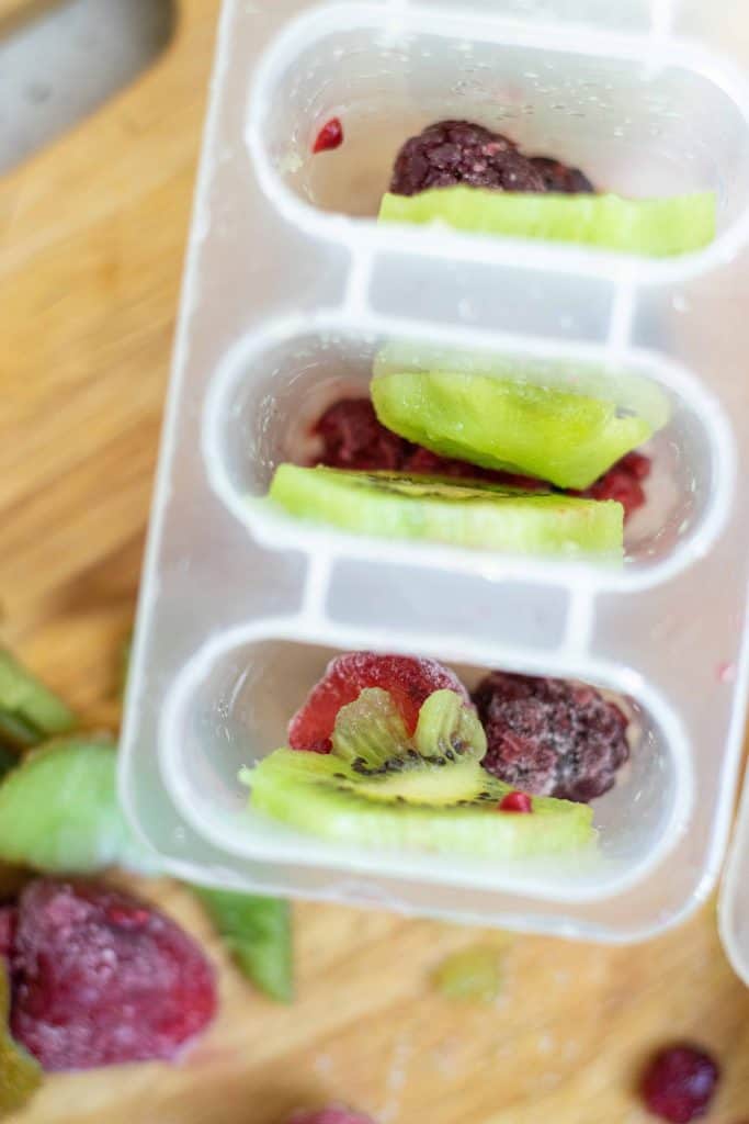 Overhead view of kiwi and berries in popsicle mold.